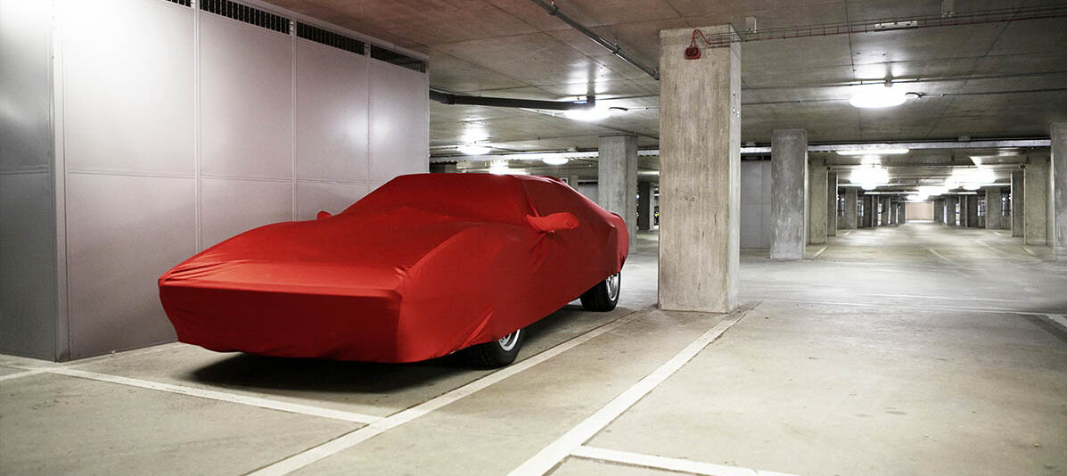 car stored in underground parking facility covered by a red tarp