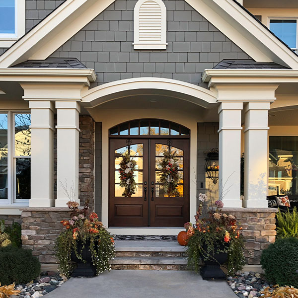 Exterior of a home with the focus on double front doors, and a landscaped walkway.