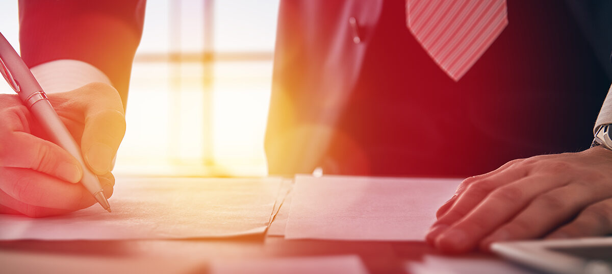 A closeup of a person holding a pen to sign a document
