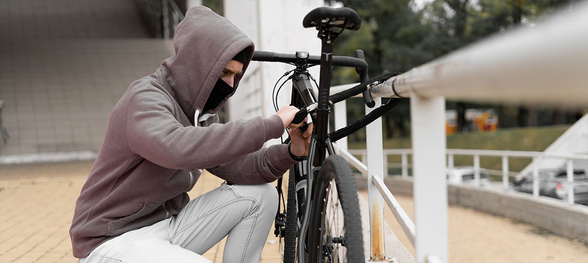Thief cutting the lock of a bike that has been chained to a railing.