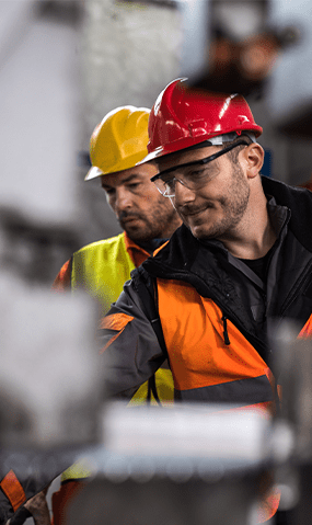 Two workers look over production in a manufacturing plant.