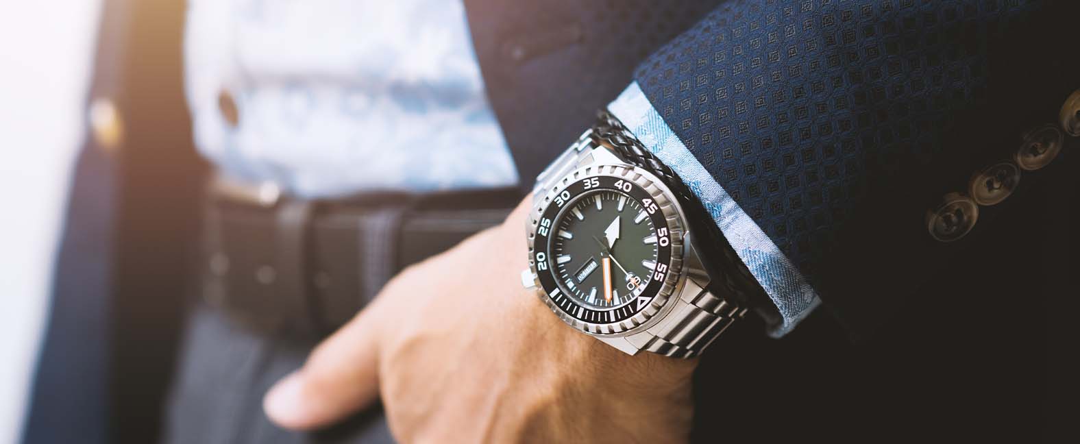 A luxury watch on the wrist of a man wearing a suit.