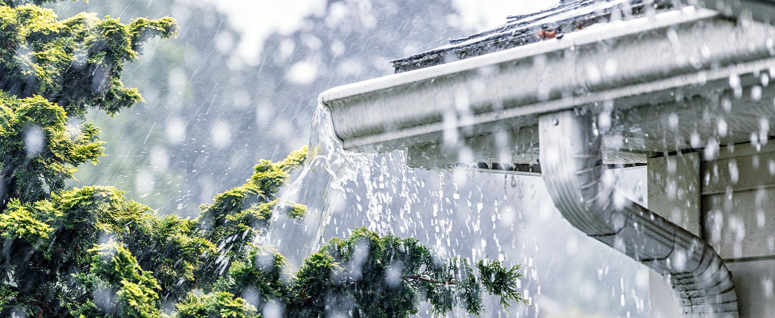 Rainfall overflows the troughs of a home.