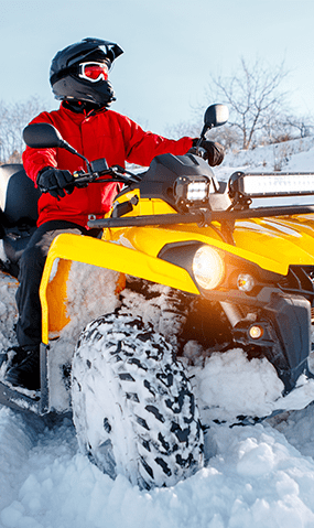 A yellow ATV traversing though snow.