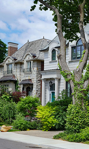 A grey brick home with a well-maintained garden.