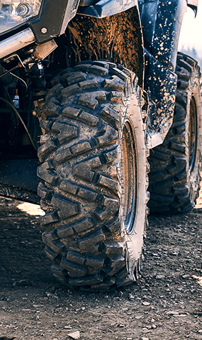 Close-up of an ATV tire covered in mud.