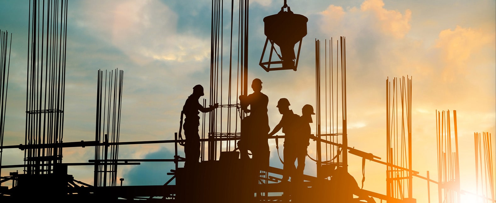 A construction crew working on a building at dusk.