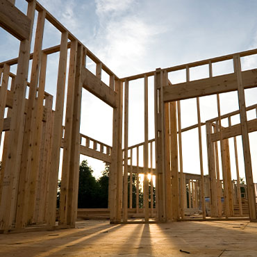The frame of a new home is constructed with additional lumber sitting in the foreground.