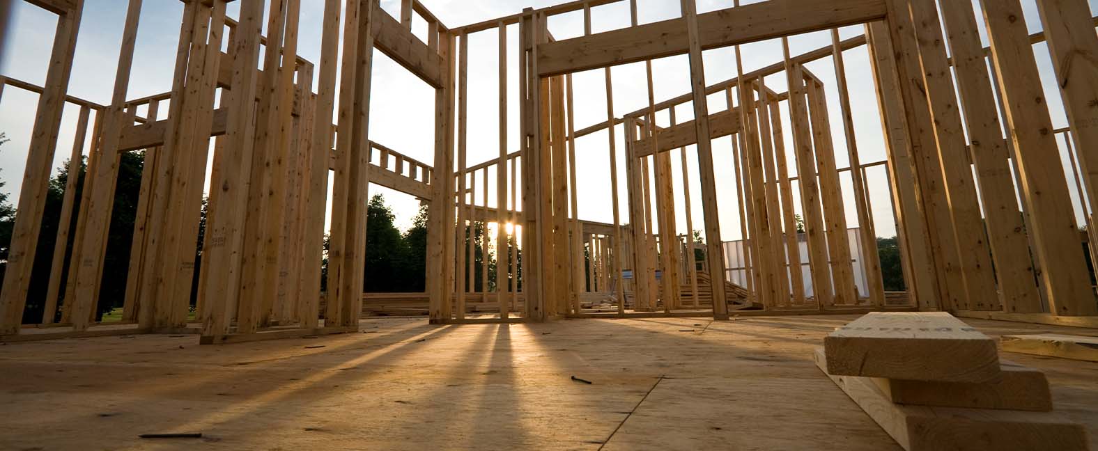 The frame of a new home is constructed with additional lumber sitting in the foreground.