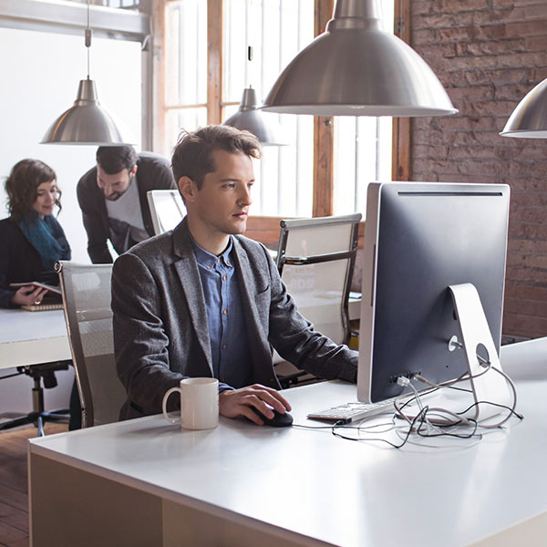 Employees sitting at workstations in a modern office workplace.