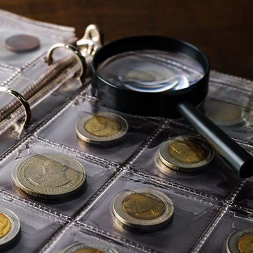 A magnifying glass sitting on a album of collector coins.