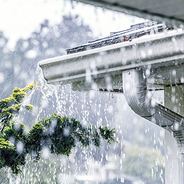Rainfall overflows the troughs of a home.