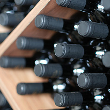 Various wine bottles are stacked on wooden racks.