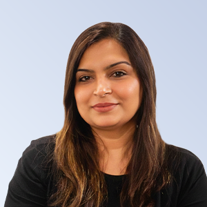 Professional portrait of a woman with long brown hair, wearing a black top, against a light blue background. She has a confident smile, ideal for business profiles or team introductions.